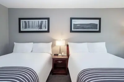 two beds in a hotel room with white sheets at Sandman Inn Cache Creek in Cache Creek