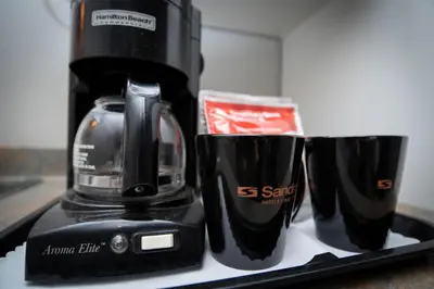 a black coffee maker and two cups on a counter at Sandman Inn Cache Creek in Cache Creek