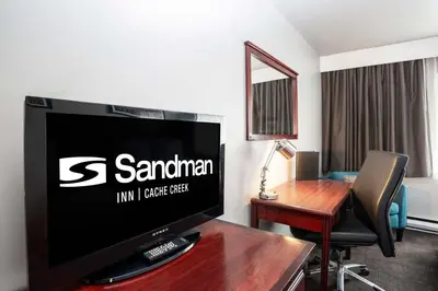 a hotel room with a flat screen tv and a desk at Sandman Inn Cache Creek in Cache Creek