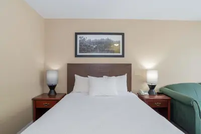 a hotel room with a bed and a blue chair at Sandman Hotel Castlegar in Castlegar