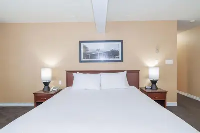 a bedroom with a large white bed with two lamps at Sandman Hotel Castlegar in Castlegar