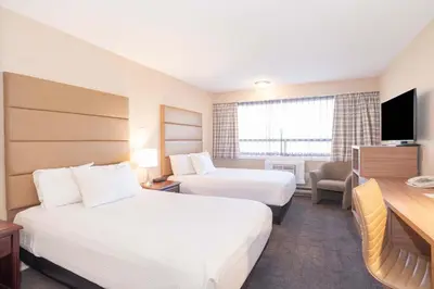a hotel room with two beds and a desk at Sandman Hotel Cranbrook in Cranbrook