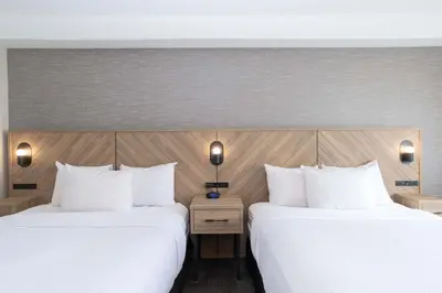 two beds in a hotel room with white pillows at Sandman Hotel Quesnel in Quesnel