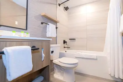 a bathroom with a white toilet and a bath tub at Sandman Hotel Quesnel in Quesnel