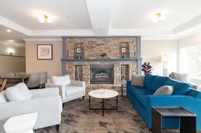 a living room with a blue couch and a fireplace at Sandman Hotel Quesnel in Quesnel