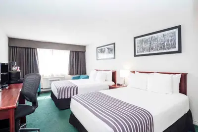 a hotel room with two beds and a desk at Sandman Inn Smithers in Smithers