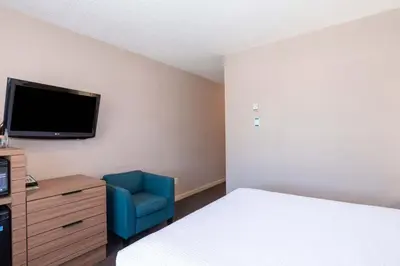 a hotel room with a bed and a blue chair at Sandman Hotel Terrace in Terrace