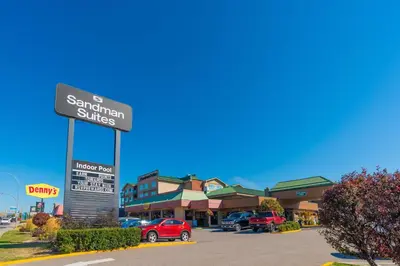a sign for a santamantam suites in a parking lot at Sandman Hotel Vernon in Vernon
