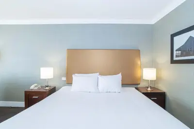 a bedroom with a large bed with two lamps at Sandman Hotel Vernon in Vernon