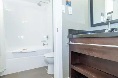 a bathroom with a toilet and a tub and a sink at Sandman Hotel Vernon in Vernon