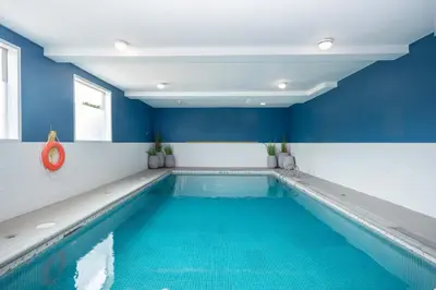 a swimming pool in a room with blue walls at Sandman Hotel Vernon in Vernon