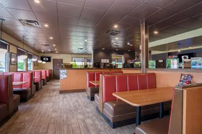 a restaurant with red chairs and a wooden table at Sandman Hotel Vernon in Vernon