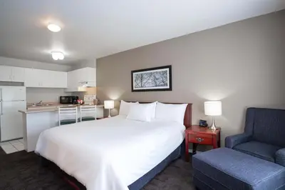 a bedroom with a white bed and a blue chair at Sandman Hotel & Suites Williams Lake in Williams Lake
