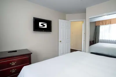 a bedroom with a bed and a clock on the wall at Sandman Hotel & Suites Williams Lake in Williams Lake