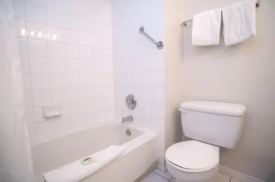 a white bathroom with a toilet and a bath tub at Sandman Hotel & Suites Williams Lake in Williams Lake