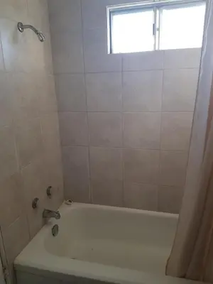 a bathroom with a bath tub and a window at Shamrock Motel in Valleyview