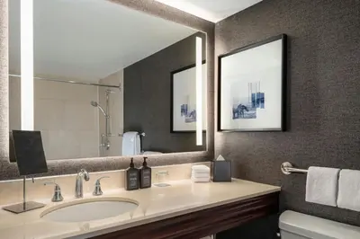 a bathroom with a sink and a large mirror at Sheraton Cavalier Calgary Hotel in Calgary