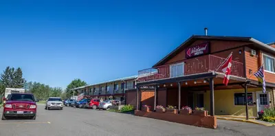 a red truck parked in front of a building at Westwood Motel 100 Mile House in One Hundred Mile House
