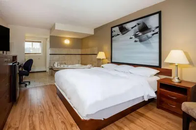 a hotel room with a large white bed and a desk at Super 8 by Wyndham Smoky Lake in Smoky Lake