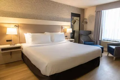 a hotel room with a large white bed and a chair at Radisson Hotel Fort St John in Fort Saint John