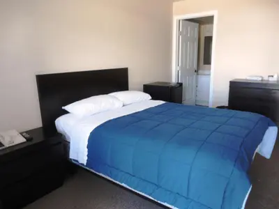 a bedroom with a large bed with a blue blanket at Stratford Motel in Whitehorse