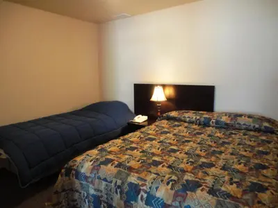a hotel room with a bed and a night stand with a lamp at Stratford Motel in Whitehorse