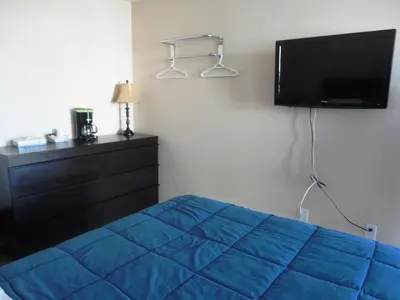 a bedroom with a blue bed and a flat screen tv at Stratford Motel in Whitehorse