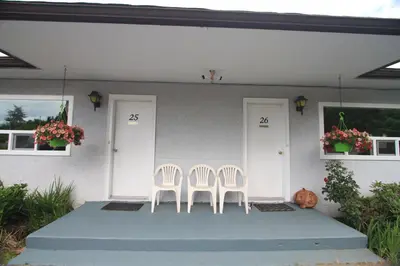 two white chairs sitting on the porch of a house at Sunset Motel & Trailer Park, Incorporated in Port Alberni