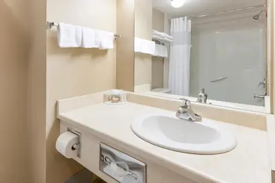 a white bathroom with a sink and a mirror at Super 8 by Wyndham Fort Saskatchewan in Fort Saskatchewan