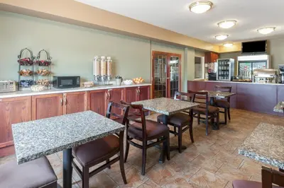 a restaurant with tables and chairs and a counter at Super 8 by Wyndham Fort Saskatchewan in Fort Saskatchewan