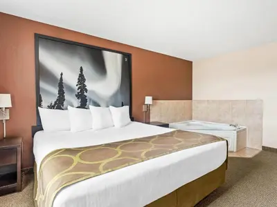 a hotel room with a large bed with a large picture on the wall at Super 8 by Wyndham Meadow Lake in Meadow Lake