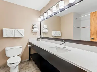 a bathroom with a sink and a toilet and a mirror at Super 8 by Wyndham Meadow Lake in Meadow Lake