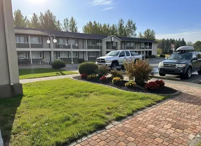 a building with two cars parked in a parking lot at Quesnel Inn in Quesnel