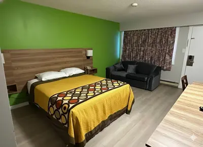 a hotel room with a bed and a chair at Quesnel Inn in Quesnel