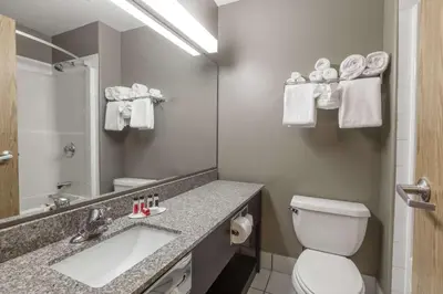 a bathroom with a toilet and a sink and a mirror at Super 8 by Wyndham Vermilion AB in Vermilion