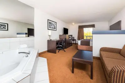 a hotel room with a bathroom and a bed at Super 8 by Wyndham Vermilion AB in Vermilion