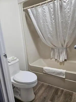a small bathroom with a toilet and a bath tub at Howard Johnson by Wyndham Hinton in Hinton