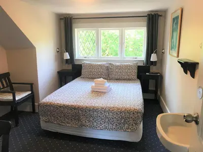 a bedroom with a bed and a window and a sink at Windsor Guest House in Vancouver
