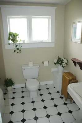 a bathroom with a toilet and a black and white tile floor at Windsor Guest House in Vancouver