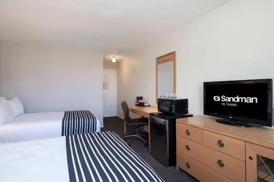 a hotel room with a bed and a desk with a television at Sandman Inn McBride in McBride