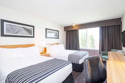 a hotel room with two beds and a desk at Sandman Inn McBride in McBride