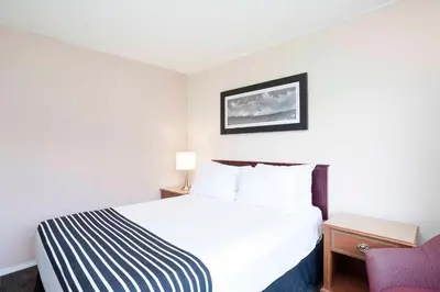 a hotel room with a bed and a chair at Sandman Inn McBride in McBride