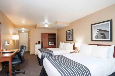 a hotel room with two beds and a desk at Sandman Inn Princeton in Princeton