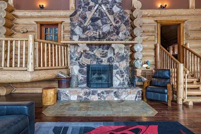 a living room with a stone fireplace in a log cabin at Spirit Lodge at Silverstar in Vernon