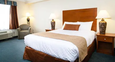 a hotel room with a large bed and a chair at Hinton Lodge in Hinton