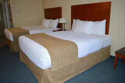 two beds in a hotel room with white sheets at Hinton Lodge in Hinton