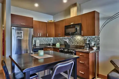 a kitchen with wooden cabinets and a table with chairs at Kookaburra Lodge #202 By Bear Country in Sun Peaks