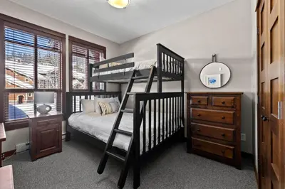 a bedroom with two bunk beds and a dresser and a bed at Stones Throw #26 By Bear Country in Sun Peaks