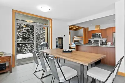 a kitchen and dining room with a wooden table and chairs at Kookaburra Lodge #203 By Bear Country in Sun Peaks