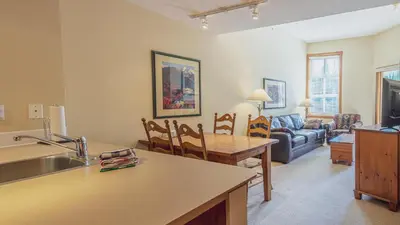 a kitchen and living room with a table and a couch at Fireside Lodge #419 By Bear Country in Sun Peaks